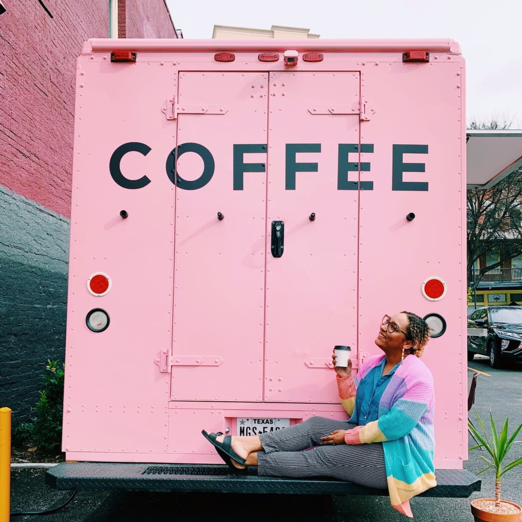 Mikayla sitting on the back bumper of a pink coffee truck