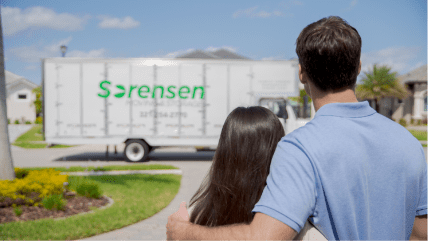 Adult couple looing at a Sorensen Moving truck parked out on the street